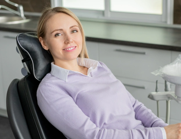 A woman smiling comfortably while sitting in a dental chair during an appointment.