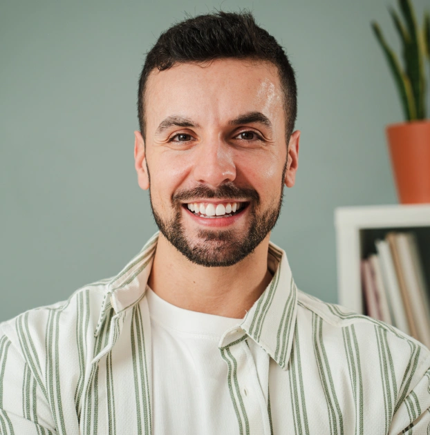 Smiling man in a green shirt displaying a healthy, confident smile.